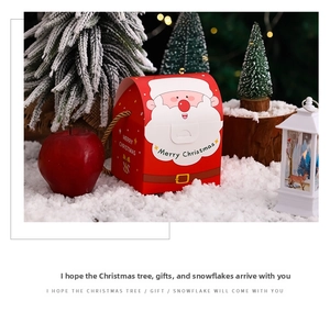Close-up of a festive red Christmas gift box with Santa motif and golden handle ropes