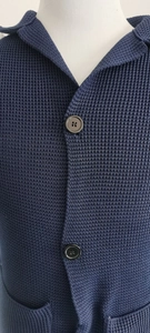 Close-up of blue waffle knit cardigan texture with black round buttons and lapel collar