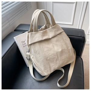 Detail of beige nylon tote bag with crinkled texture on a black leather sofa
