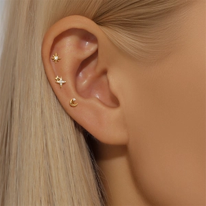Macro shot of gold star and moon stud earrings set with sparkling zircons on ear