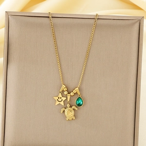 Detailed view of gold ocean necklace with turtle, star, and green gemstone charms