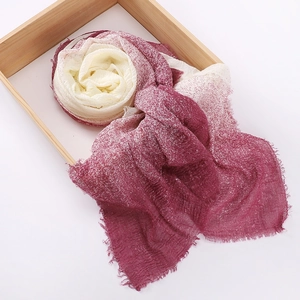 Red and white gradient tie-dye scarf with fringe edges on a minimalist wooden tray
