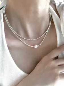 Double-layered S925 sterling silver necklace featuring a white round pearl on a model