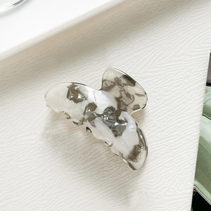 Detailaufnahme einer kleinen Haarspange mit Marmormuster auf weißer Oberfläche