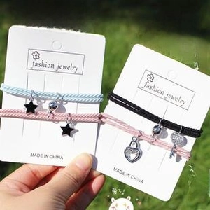 Détail de bracelets tressés pour couple avec breloques magnétiques et cœur sur herbe