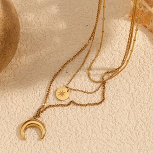 Close-up of layered 18K gold-plated necklaces featuring star coin and crescent moon pendants