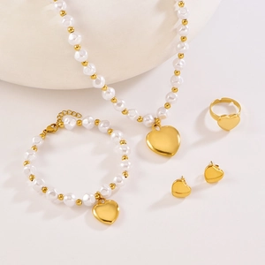 Detail of gold heart pendant and pearl jewelry set including necklace and earrings