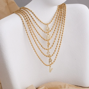 Detail of 18K gold beaded chain necklaces featuring zircon-encrusted alphabet pendants