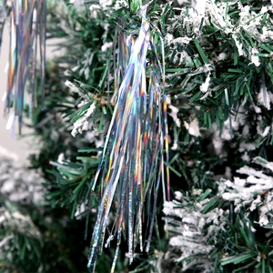 Iridescent silver tinsel garland hanging on a snowy Christmas tree branch decor