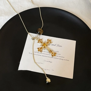 Detail of cross pendant with amber rhinestones and tiger eye bead on gold chain