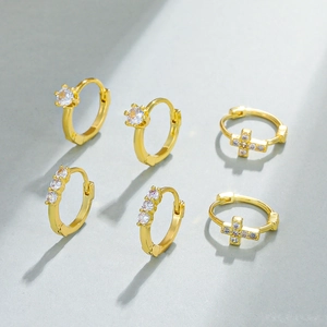 Set of three pairs of gold huggie earrings featuring sparkling cross and zircon designs