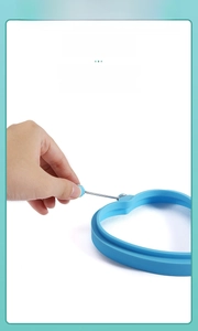 Blue silicone heart-shaped egg ring with an insulated metal handle for safe lifting