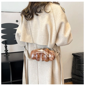 Pochette in acrilico marmorizzato marrone con catena in argento su un cappotto beige