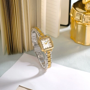 Montre à quartz carrée élégante or et argent avec chiffres romains sur un bureau