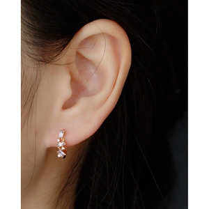 Detail of U-shaped gold earrings with purple cubic zirconia stones on model