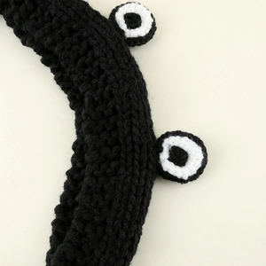 Detail of hand-knitted black thick wool headband with cute cartoon frog eyes crochet texture