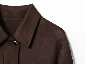 Détail macro du col d'une veste en daim marron foncé avec bouton métallique noir