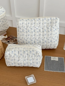 Detail of floral quilted makeup bag with blue flower pattern and small bow accent