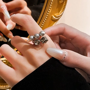 Detail of silver-tone ring featuring gray pearls and a square-cut dark crystal