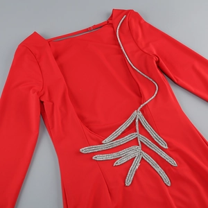 Detail of red long sleeve dress featuring deep U-back design and silver sequin leaf patterns