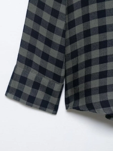 Dettaglio macro dei polsini di una camicia a quadri neri e grigi con trama fine