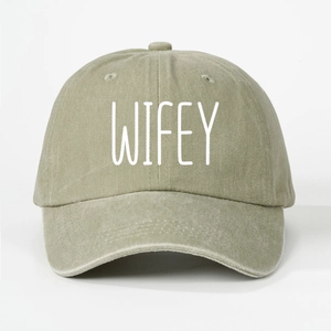 Close-up detail of white WIFEY embroidery on washed khaki olive baseball cap soft crown