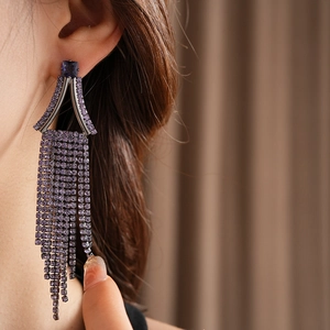 Macro shot of purple rhinestone tassel earrings with square blue gemstone detail