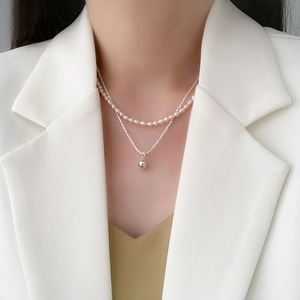 Close-up of double-layer necklace with white freshwater pearls and silver round pendant