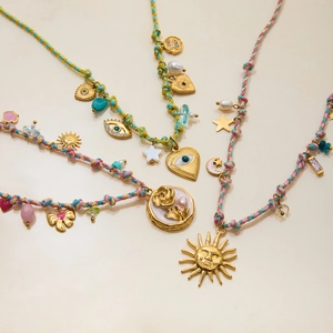 Detail of multi-strand woven necklaces with 18K gold sun and star charms and pearls