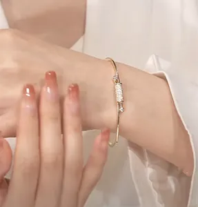 Detailed close-up of a gold bangle with a sparkling cubic zirconia knot design on wrist