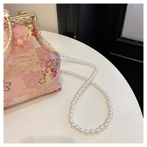 Detailed macro view of pink floral embroidery and pearl handle on a luxury handbag
