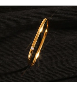 Close-up of a minimalist gold ring featuring a sparkling micro-set zircon on polished band