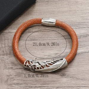 Brown leather punk bracelet with silver feather charm and dimensions on wood background