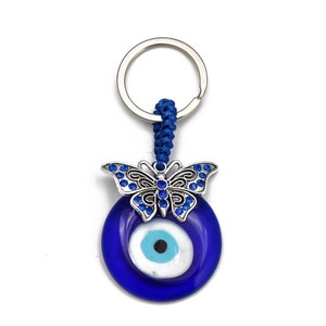 Detail of blue Evil Eye keychain with silver butterfly charm and tassel on white background