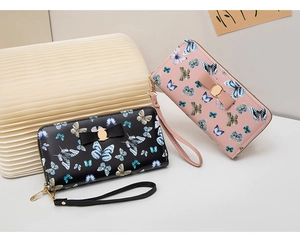 Detail view of long PU leather wallets in black and pink with butterfly print and wrist straps