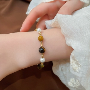Detail of beaded bracelet featuring pearls, tiger eye stones and gold spiral spacers