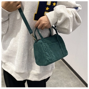 Detailed texture of green corduroy Boston bag with detachable shoulder strap and handles