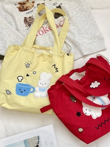 Grandi borse tote in tela ricamata con chiusura a coulisse nei vivaci colori rosso e giallo