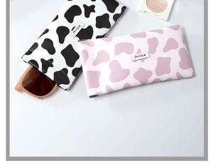 Detail view of the cow print leather eyewear pouch with spring closure in pink and black