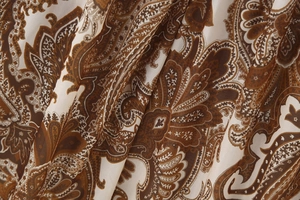 Vue détaillée du motif paisley marron sur tissu crème avec une texture souple et drapée