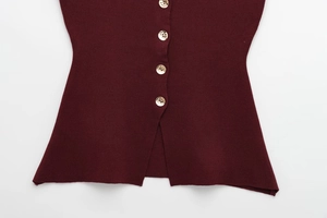 Gros plan d'un gilet en tricot bordeaux avec boutons dorés et fente latérale discrète
