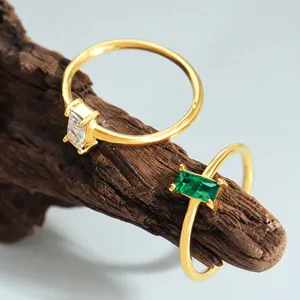 Dettaglio di anelli minimalisti dorati con pietre preziose rettangolari su base di legno