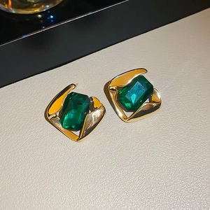 Macro detail of vintage gold square earrings with emerald green rectangular gemstone