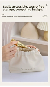 Macro view of creamy white drawstring PU leather makeup bag with gold accessories