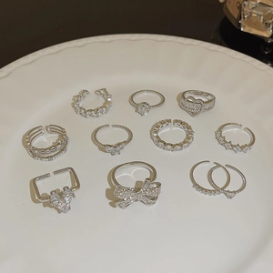 Set of 10 silver butterfly and heart rings with zircons in a white ceramic dish