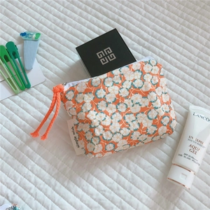 Close-up of floral cotton mini pouch with orange zipper pull and simple wish label