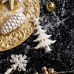 Elegant white and gold Christmas tree ornaments set with star and pinecone on luxury plate