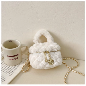Detail of white plush quilted bag featuring a golden rose charm and chain strap