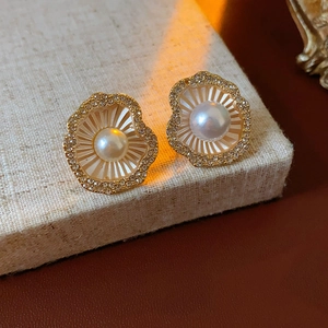 Vue macro de boucles d'oreilles coquillage dorées avec perle blanche et cristaux