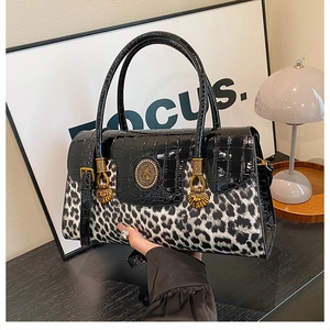 Close-up of luxury leopard print and crocodile texture handbag with gold lion hardware